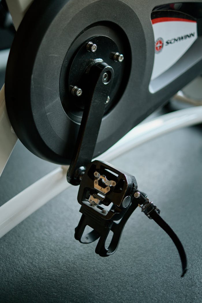 why-choose-us Detailed view of an exercise bike pedal and crank in a fitness center.